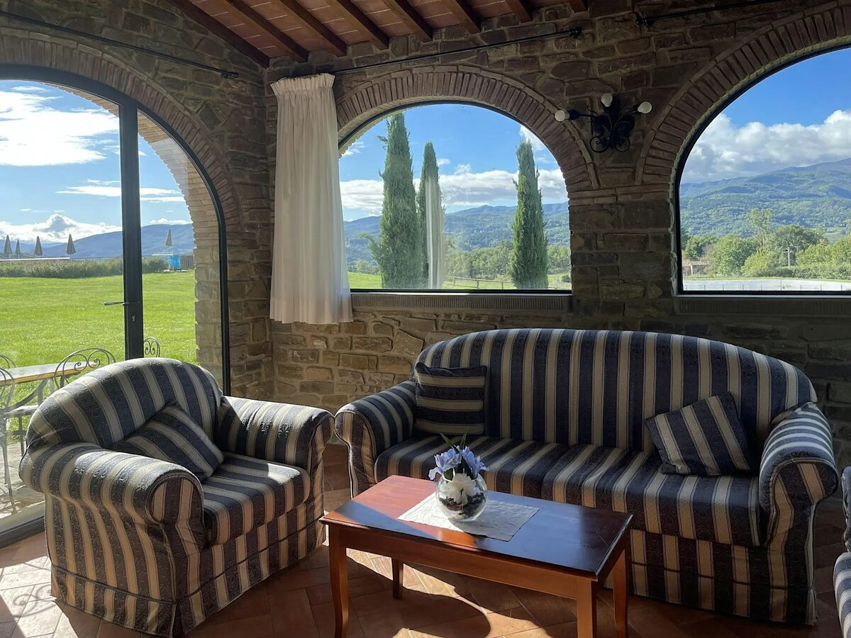 Stone lounge with arched windows and Tuscan views
